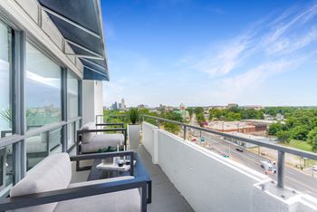 A balcony with a table and chairs overlooking a busy street.